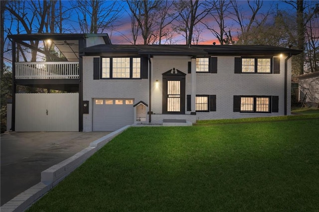 split foyer home featuring a garage, driveway, brick siding, and a front yard