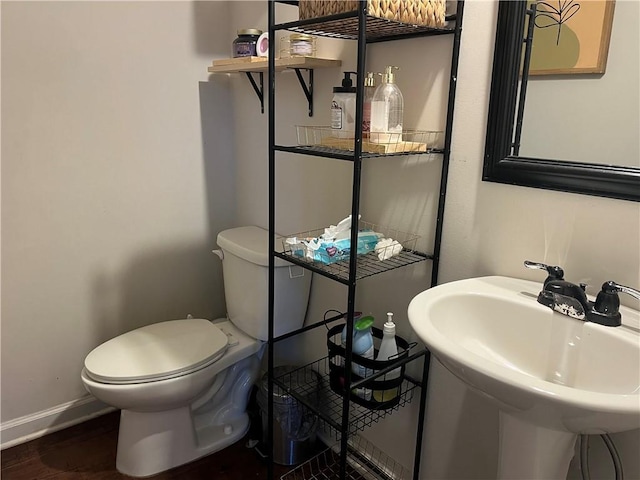 bathroom with a sink, baseboards, toilet, and wood finished floors