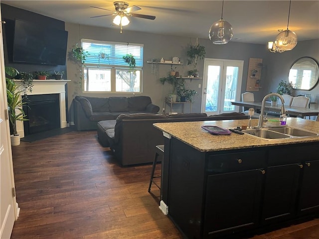 kitchen with a sink, dark wood finished floors, a breakfast bar area, a fireplace, and dark cabinets