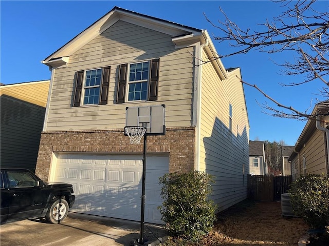 view of home's exterior with brick siding, an attached garage, driveway, and fence