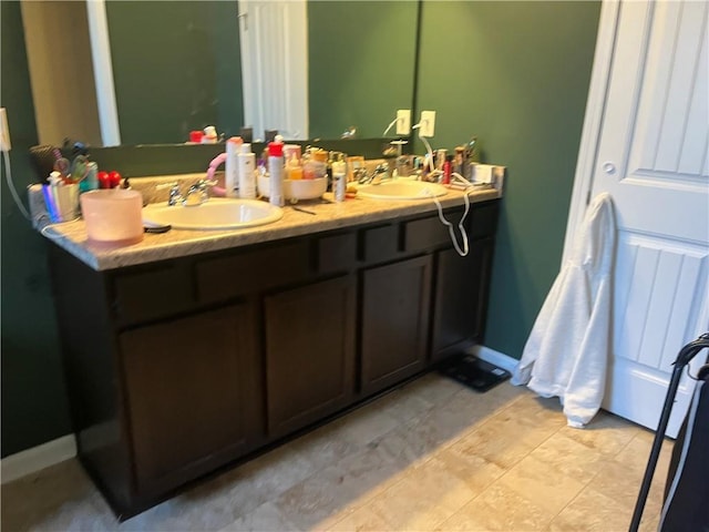 bathroom featuring double vanity, baseboards, and a sink