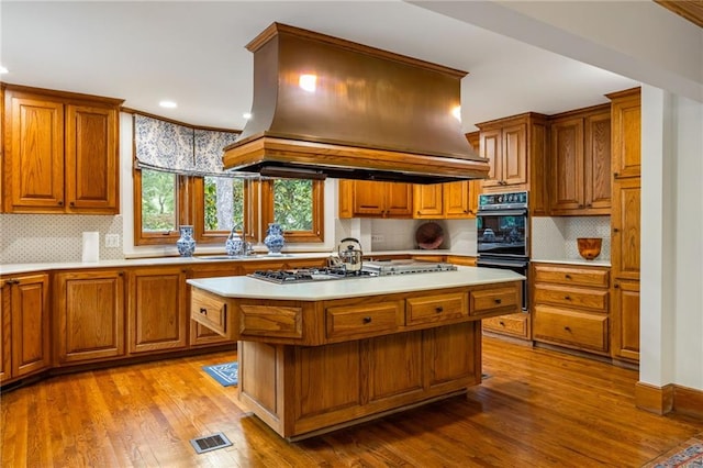 44 Muscogee Ave NW, Atlanta, GA 30305 - kitchen with island exhaust hood, a sink, brown cabinetry, and recessed lighting