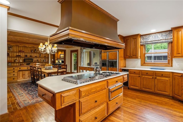 44 Muscogee Ave NW, Atlanta, GA 30305 - kitchen with island exhaust hood, a chandelier, a warming drawer, brown cabinets, and light wood-type flooring