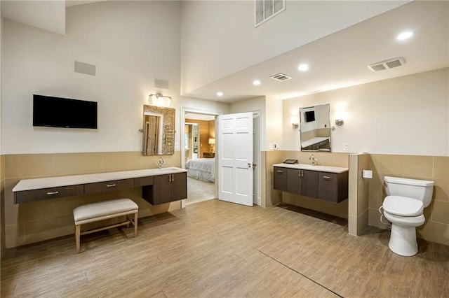 44 Muscogee Ave NW, Atlanta, GA 30305 - bathroom with tile walls, connected bathroom, toilet, wood finished floors, and two vanities