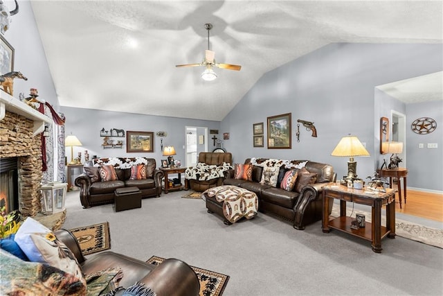 living area featuring high vaulted ceiling, a ceiling fan, carpet flooring, and a stone fireplace