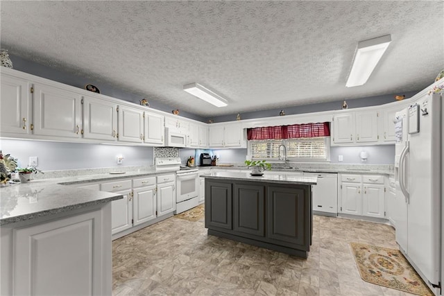 kitchen featuring light stone countertops, white appliances, white cabinetry, and a sink