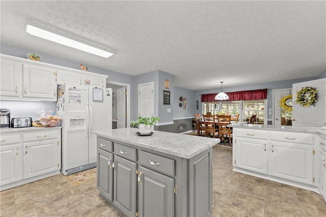 kitchen featuring white refrigerator with ice dispenser, white cabinets, and gray cabinetry