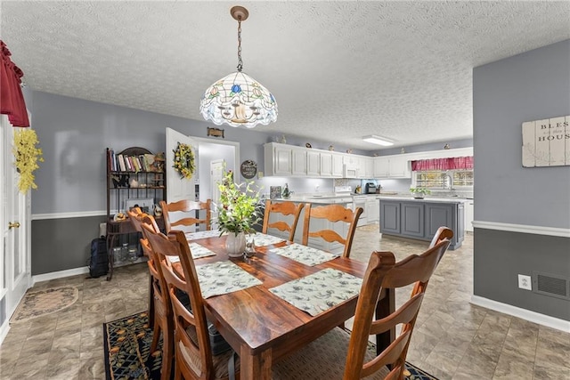 dining room featuring baseboards, visible vents, and a textured ceiling