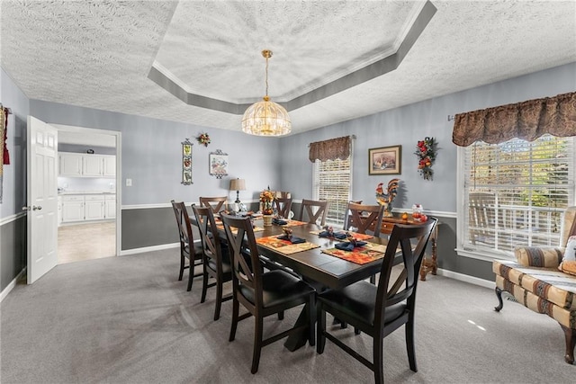 dining space featuring plenty of natural light, a chandelier, a raised ceiling, and light colored carpet