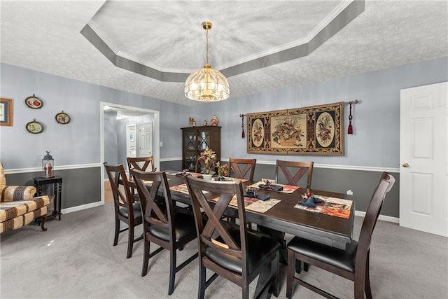 dining area with carpet floors, ornamental molding, a raised ceiling, and a textured ceiling