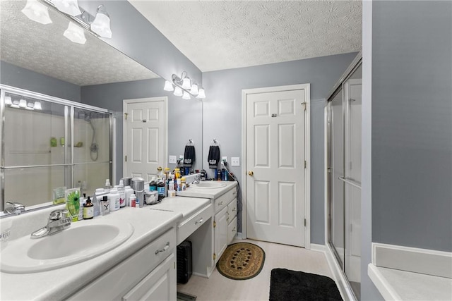 bathroom with a sink, double vanity, a textured ceiling, and a shower stall