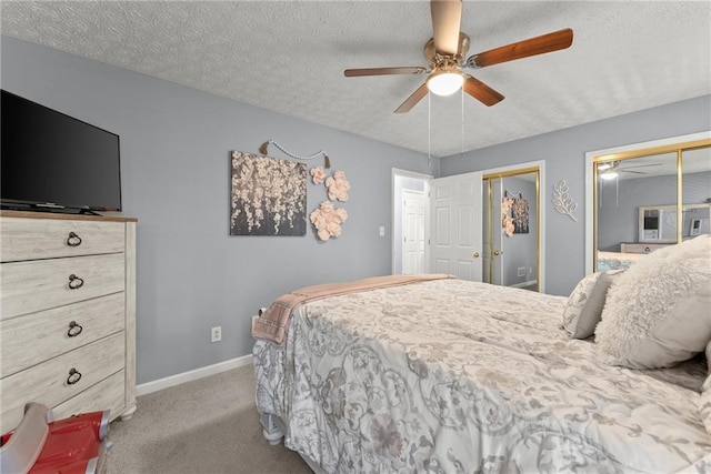 bedroom featuring a textured ceiling, ceiling fan, carpet flooring, baseboards, and multiple closets