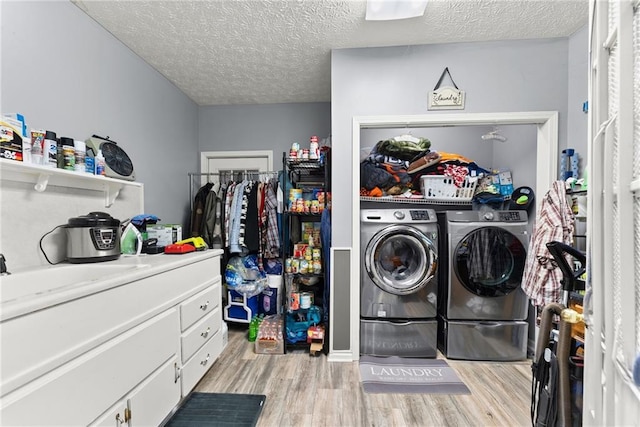 laundry room with laundry area, light wood finished floors, a textured ceiling, washing machine and dryer, and a sink