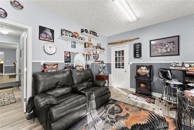 living area with a textured ceiling, wood finished floors, and a wood stove