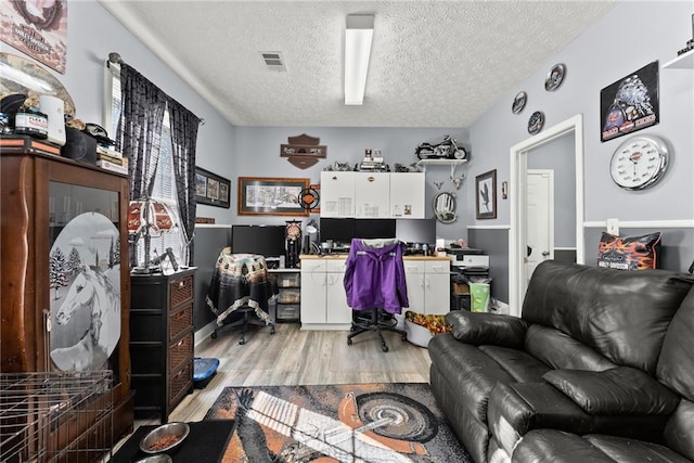 home office featuring light wood-style flooring and a textured ceiling