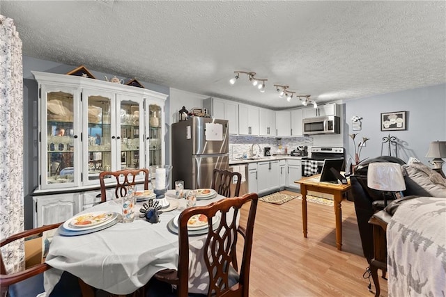 dining room with light wood-type flooring and a textured ceiling