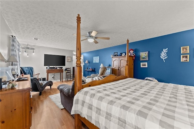 bedroom featuring light wood-style flooring, visible vents, ceiling fan, and a textured ceiling