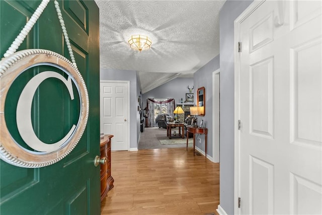 entryway featuring baseboards, a textured ceiling, and light wood finished floors