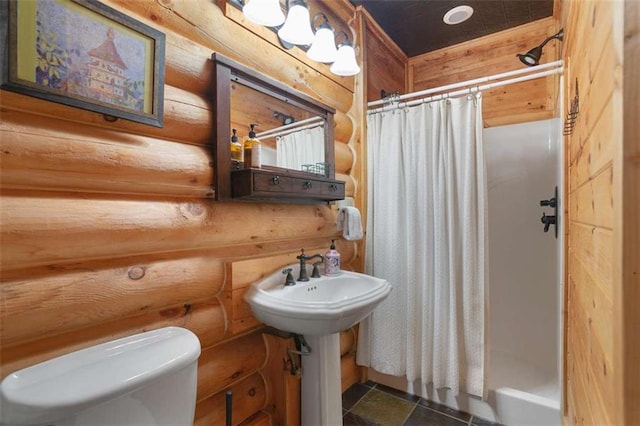 bathroom featuring curtained shower, toilet, and rustic walls