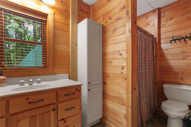 bathroom featuring walk in shower, vanity, toilet, and wood walls