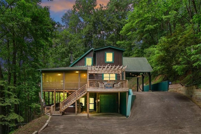 back house at dusk featuring a garage and a deck