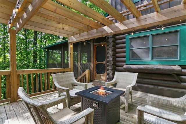 wooden terrace featuring a pergola, a fire pit, and a sunroom