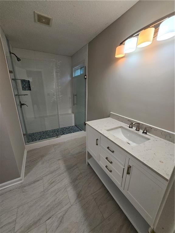 bathroom with vanity, a shower with door, and a textured ceiling