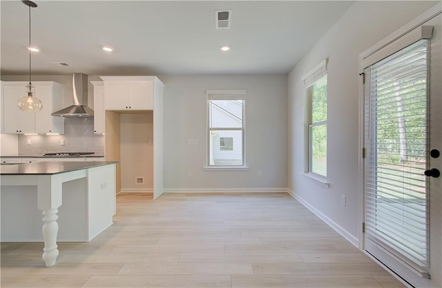 kitchen with tasteful backsplash, visible vents, white cabinets, dark countertops, and wall chimney exhaust hood