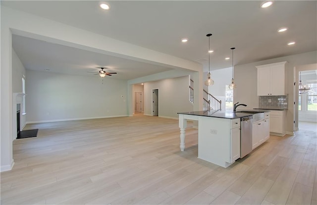 kitchen with a breakfast bar, a fireplace, decorative backsplash, dishwasher, and dark countertops