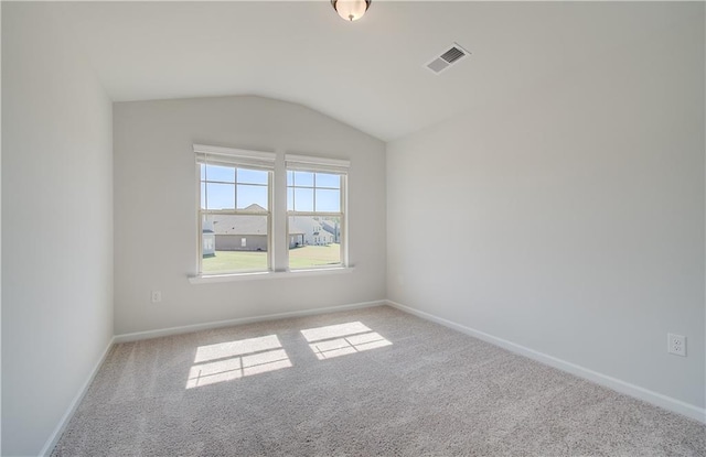 carpeted spare room featuring visible vents, vaulted ceiling, and baseboards