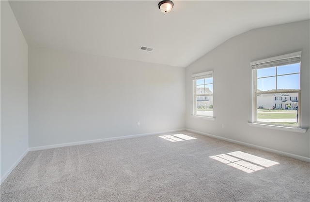 carpeted spare room with visible vents, baseboards, and vaulted ceiling