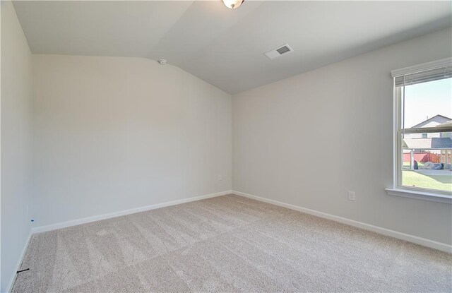 carpeted spare room featuring lofted ceiling, visible vents, and baseboards