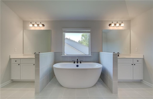 bathroom featuring tile walls, a soaking tub, two vanities, a sink, and tile patterned floors