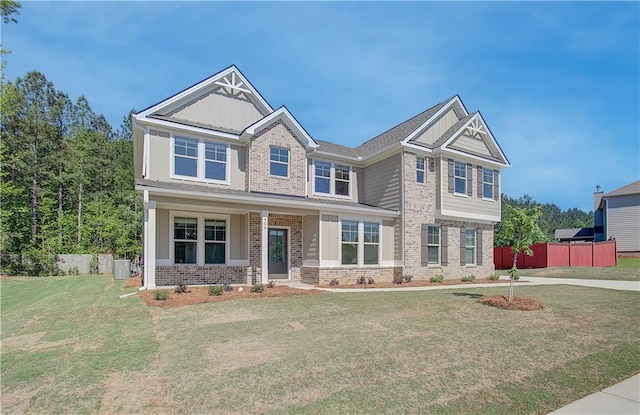 craftsman house featuring board and batten siding, brick siding, fence, and a front lawn