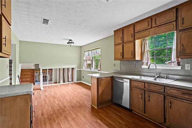 140 Carriage Cir, Stockbridge, GA 30281 - kitchen with dishwasher, wood finished floors, backsplash, brown cabinets, and a peninsula
