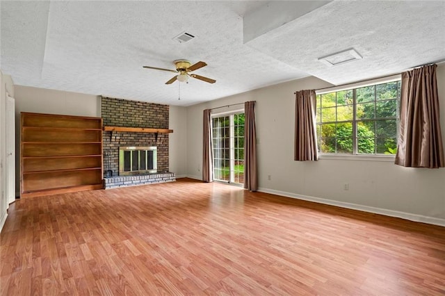 140 Carriage Cir, Stockbridge, GA 30281 - unfurnished living room featuring light wood-style flooring, a textured ceiling, a ceiling fan, and a fireplace