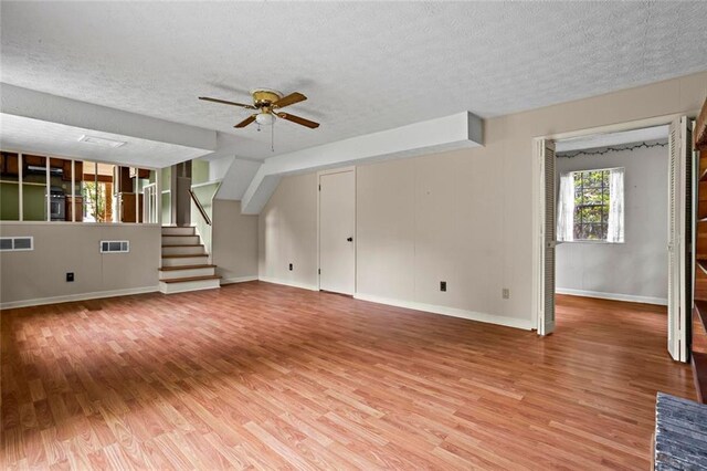 140 Carriage Cir, Stockbridge, GA 30281 - unfurnished living room featuring a textured ceiling, light wood-style floors, ceiling fan, and stairs