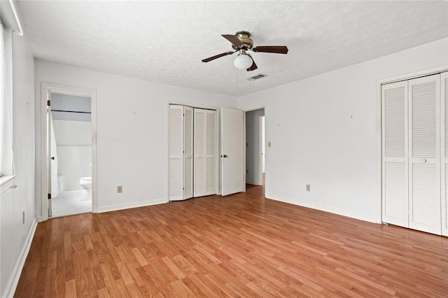 140 Carriage Cir, Stockbridge, GA 30281 - unfurnished bedroom with light wood finished floors, two closets, ensuite bath, a textured ceiling, and a ceiling fan