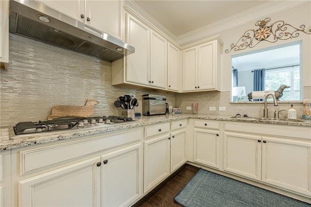 5515 Cheatam Ave, Cumming, GA 30040 - kitchen featuring under cabinet range hood, stainless steel gas cooktop, decorative backsplash, crown molding, and dark wood-style floors
