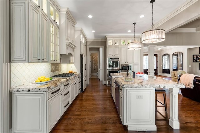 341 Carl Sanders Dr, Acworth, GA 30101 - kitchen featuring open floor plan, appliances with stainless steel finishes, ornate columns, a kitchen breakfast bar, and dark wood-type flooring