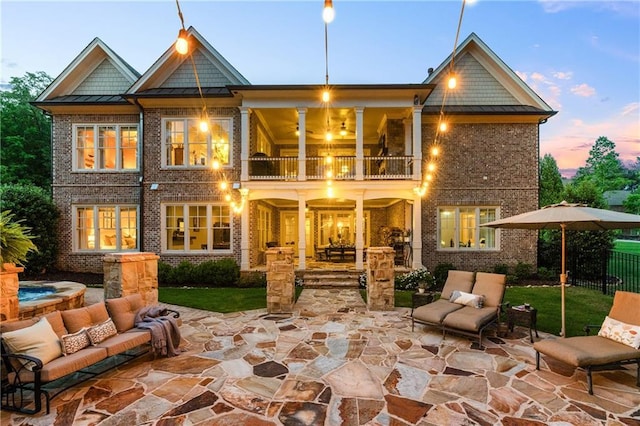 341 Carl Sanders Dr, Acworth, GA 30101 - back of property at dusk with a balcony, a standing seam roof, outdoor lounge area, a patio area, and brick siding