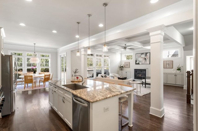 kitchen with a kitchen island with sink, stainless steel appliances, light stone counters, coffered ceiling, and white cabinets