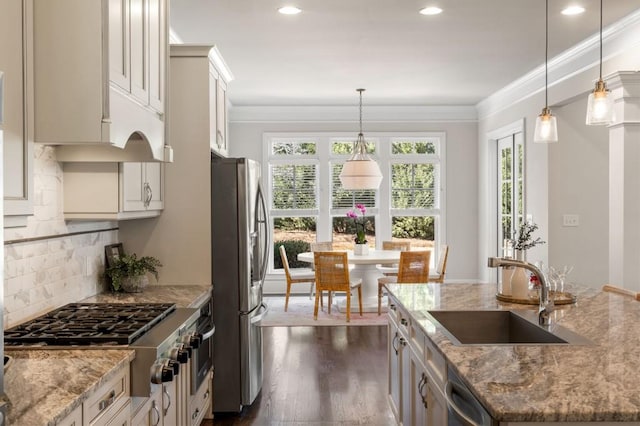 kitchen with sink, decorative light fixtures, light stone countertops, and appliances with stainless steel finishes