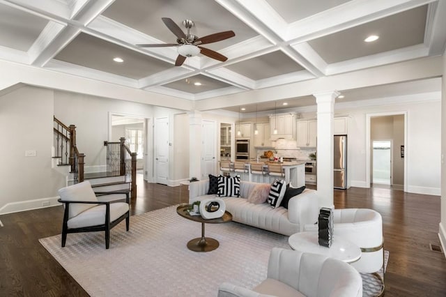 living room with ceiling fan, dark hardwood / wood-style floors, coffered ceiling, beamed ceiling, and ornate columns