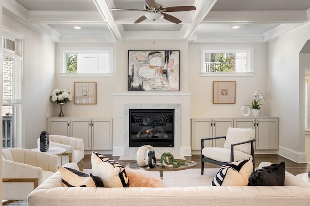 living room featuring hardwood / wood-style flooring, beam ceiling, coffered ceiling, a fireplace, and ornamental molding