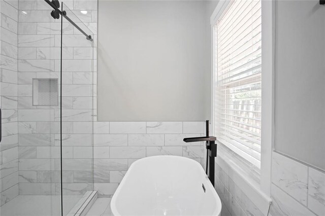 bathroom featuring tile walls and separate shower and tub