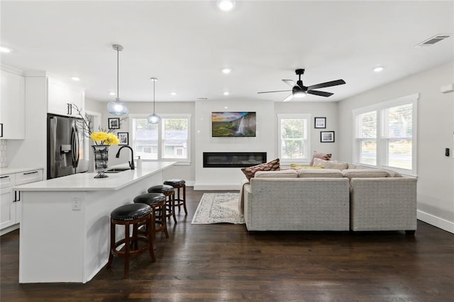 living room featuring ceiling fan, sink, and dark hardwood / wood-style floors