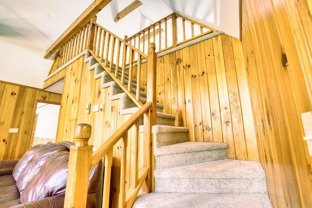 staircase with wood walls and high vaulted ceiling