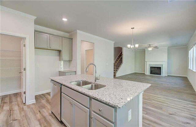 kitchen with light stone countertops, sink, stainless steel dishwasher, a center island with sink, and light wood-type flooring