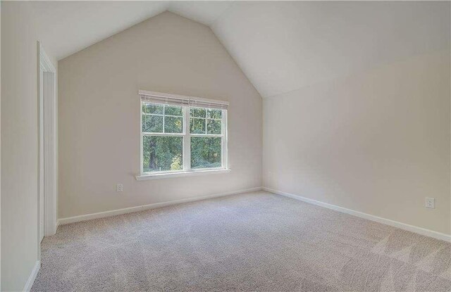 carpeted empty room with lofted ceiling